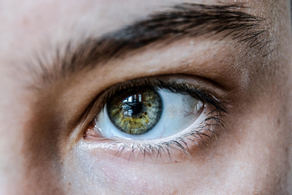 A person's hands gently open, revealing a vibrant, crisply focused natural landscape beyond, while a blurred pair of eyeglasses lies discarded in the foreground, symbolizing regained clarity and natural vision improvement.