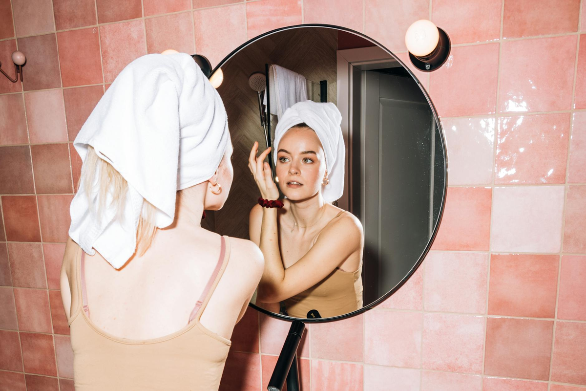 A serene, close-up shot of a person's face, meticulously receiving a multi-step skincare application, with distinct, translucent layers of product visibly settling onto the skin, conveying strategic precision and optimal absorption.