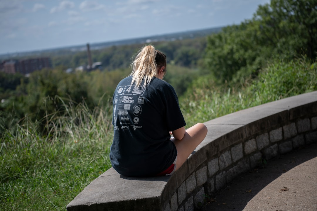 A serene individual with over-ear headphones sitting peacefully in a minimalist, soft-lit space, with gentle, luminous sound waves visually emanating from the headphones, enveloping them in calm.