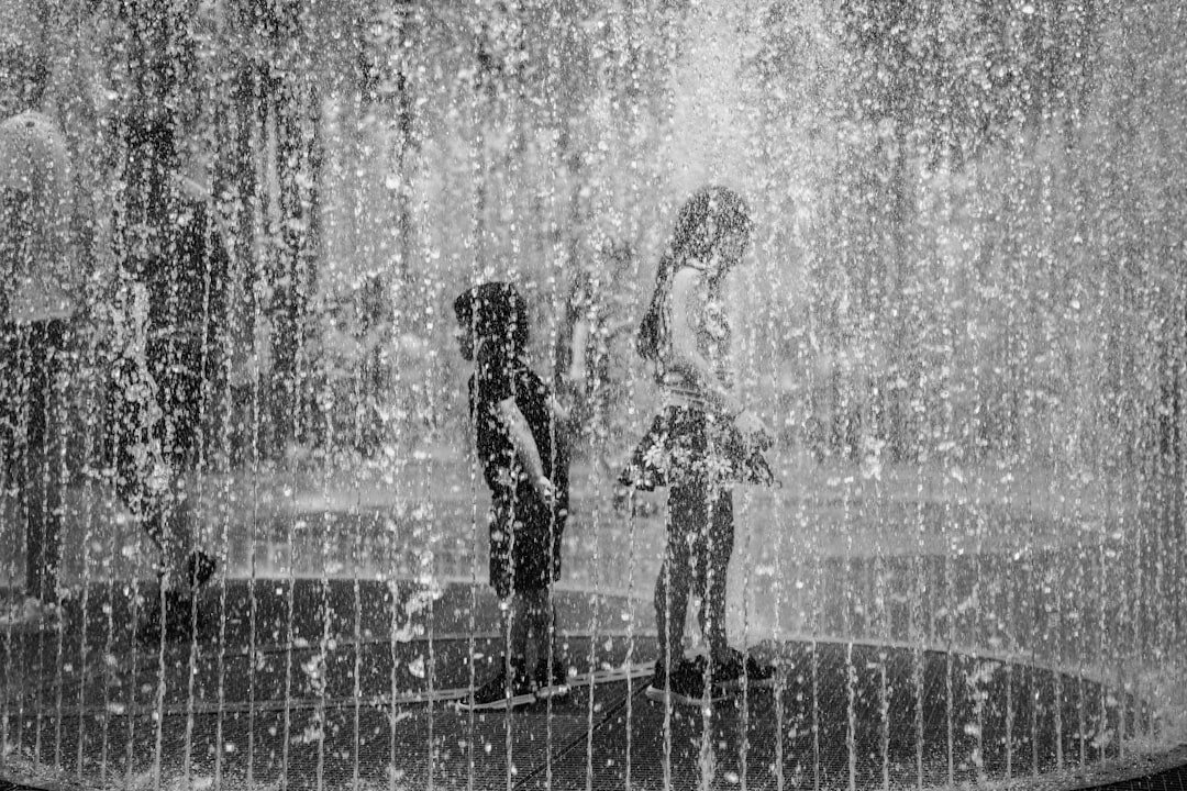 A close-up of bare feet standing on a shower floor, with cascading water visibly transitioning from clear to an icy blue gradient as it pools, symbolizing the gradual adaptation and increasing intensity of cold thermogenesis practices.