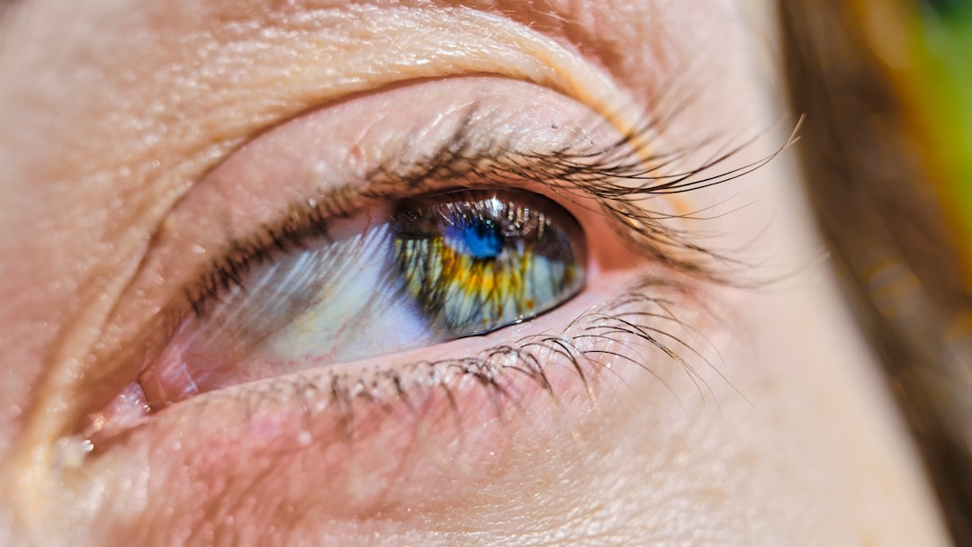 A close-up of a human eye with a translucent, swirling haze of microscopic particulate matter and subtle chemical symbols partially obscuring the pupil, subtly depicting vision degradation from environmental toxins.