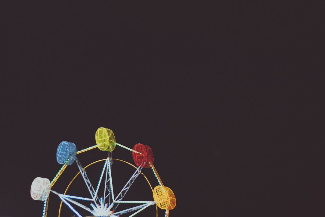 Precisely illuminated Ferris wheel with vibrant multi-colored pods against a deep, dark night sky, conveying a sense of serene focus.