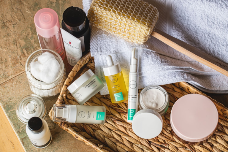Neatly arranged skincare products, prominently featuring Poko eye cream, facial oils, and moisturizers in a wicker basket with a towel and loofah, suggesting a serene self-care and eye health regimen.