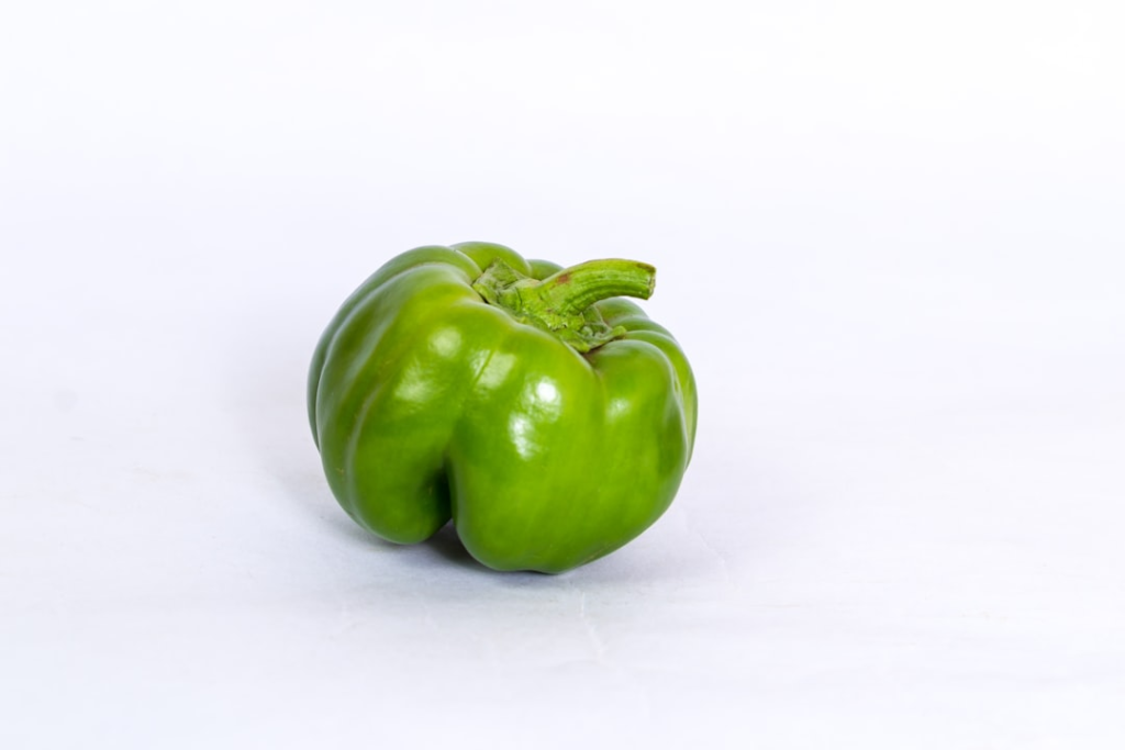 Vibrant green bell pepper on a clean white background symbolizes a fresh, nutrient-rich food essential for gut health and digestive wellness.