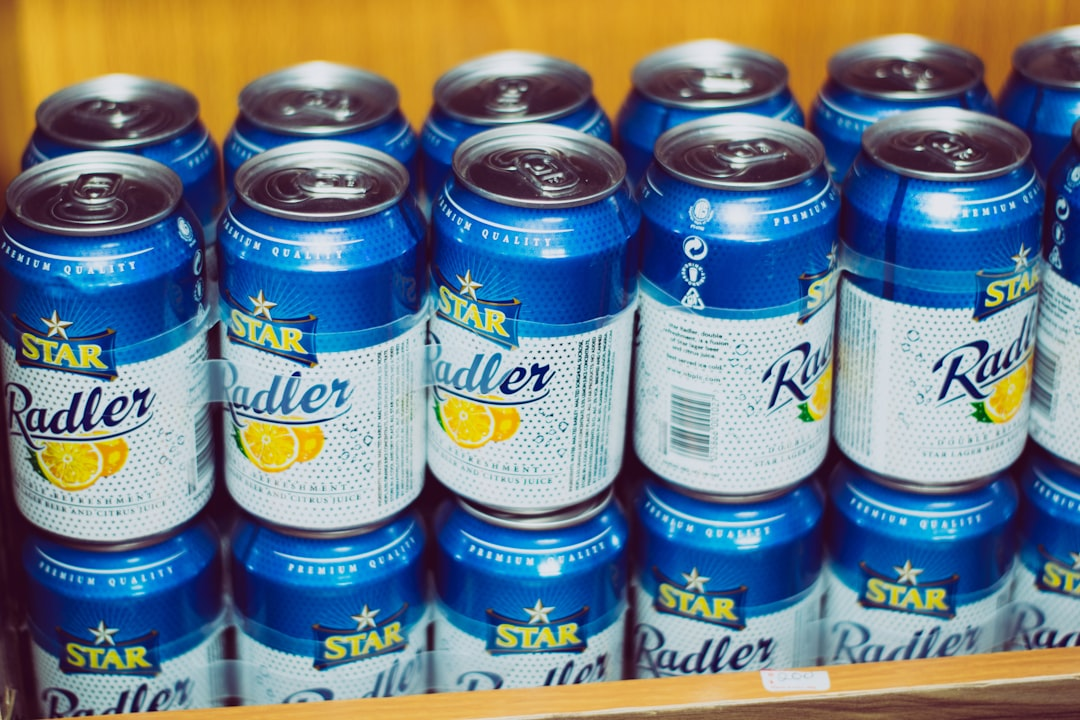 Rows of refreshing blue and white Star Radler beverage cans, featuring citrus fruit illustrations, neatly stacked on a wooden display, ready for invigorating cold consumption.