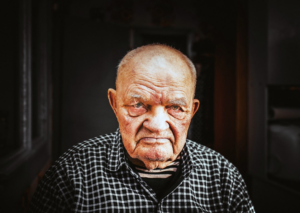 Close-up portrait of an older man with a deeply wrinkled face and serious expression, representing the profound visible effects of aging and the journey towards longevity.