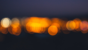 Vibrant, diffuse bokeh lights in warm orange and yellow glow against a deep blue-black night, symbolizing the energetic boost of cellular detoxification.