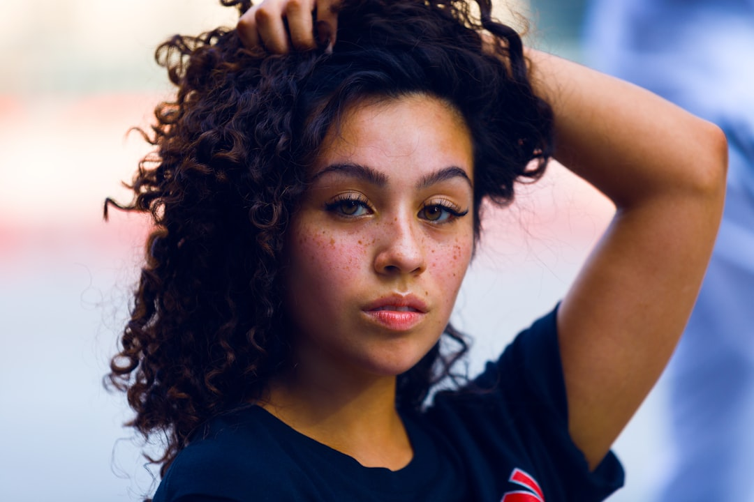 A confident young woman with luscious dark curly hair and radiant, healthy skin, embodying natural beauty and vitality.