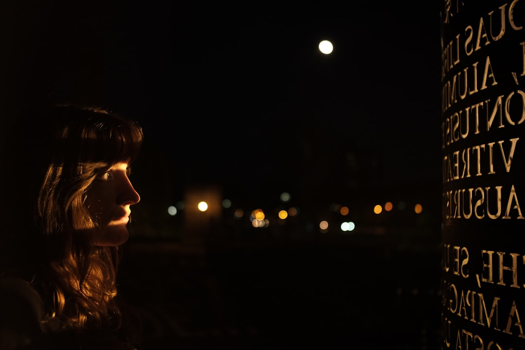 A woman's face, illuminated by warm light against a dark night sky with distant city lights and an engraved monument, suggests a contemplative hope for innovative light therapy in glaucoma treatment.