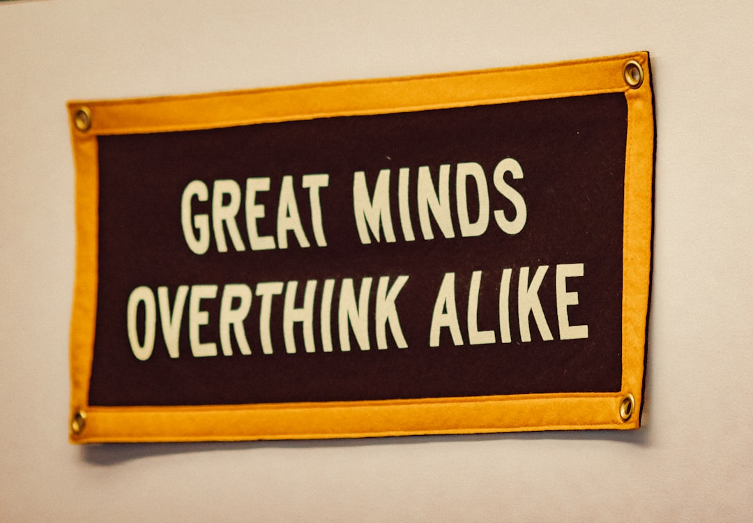 Humorous brown felt banner with a yellow border displaying the white text GREAT MINDS OVERTHINK ALIKE, thoughtfully connecting to cognitive patterns and the pursuit of optimal mental states.