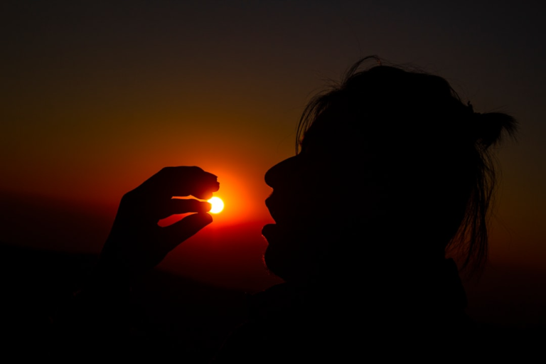 A person's silhouette appears to hold the vibrant setting sun, symbolizing the capture of powerful energy for radiant health and overall vitality.