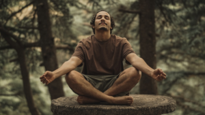 A man meditates serenely with eyes closed in a cross-legged pose on a tree stump in a calm forest, representing peaceful mindfulness for enhanced meditation.