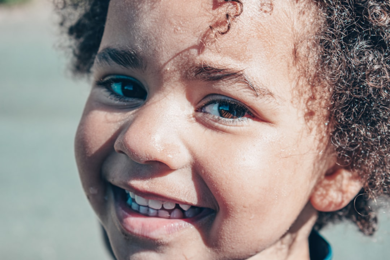 A joyful child with bright, healthy eyes and a wide smile, reflecting clear vision and overall well-being.