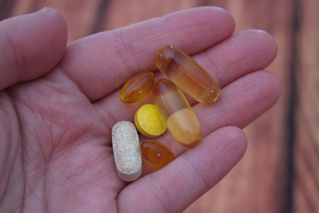 A hand holds a variety of health supplements, including clear softgel capsules and a tablet, emphasizing the role of nutritional support in holistic wellness for the gut-eye-brain axis, sleep, and vision.
