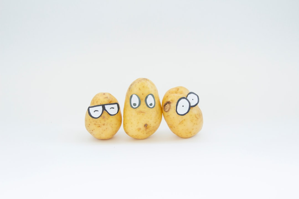 Three animated potatoes with drawn faces – one with glasses, one with wide eyes, and one with misaligned googly eyes – are playfully arranged on a white background, symbolizing fuel sources for the body's metabolism.