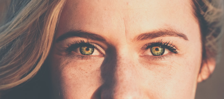 Close-up of a woman's bright green eyes with visible fine lines, emphasizing the importance of eye health and clear vision in the context of age-related macular degeneration.